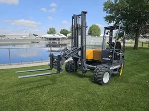 Forklift parked on grass near water, showcasing Moffett truck mounted forklift in a tranquil setting.